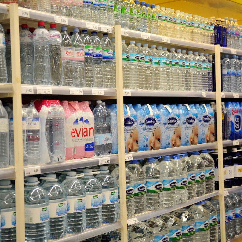 Shelves full of bottled water for sale in supermarket